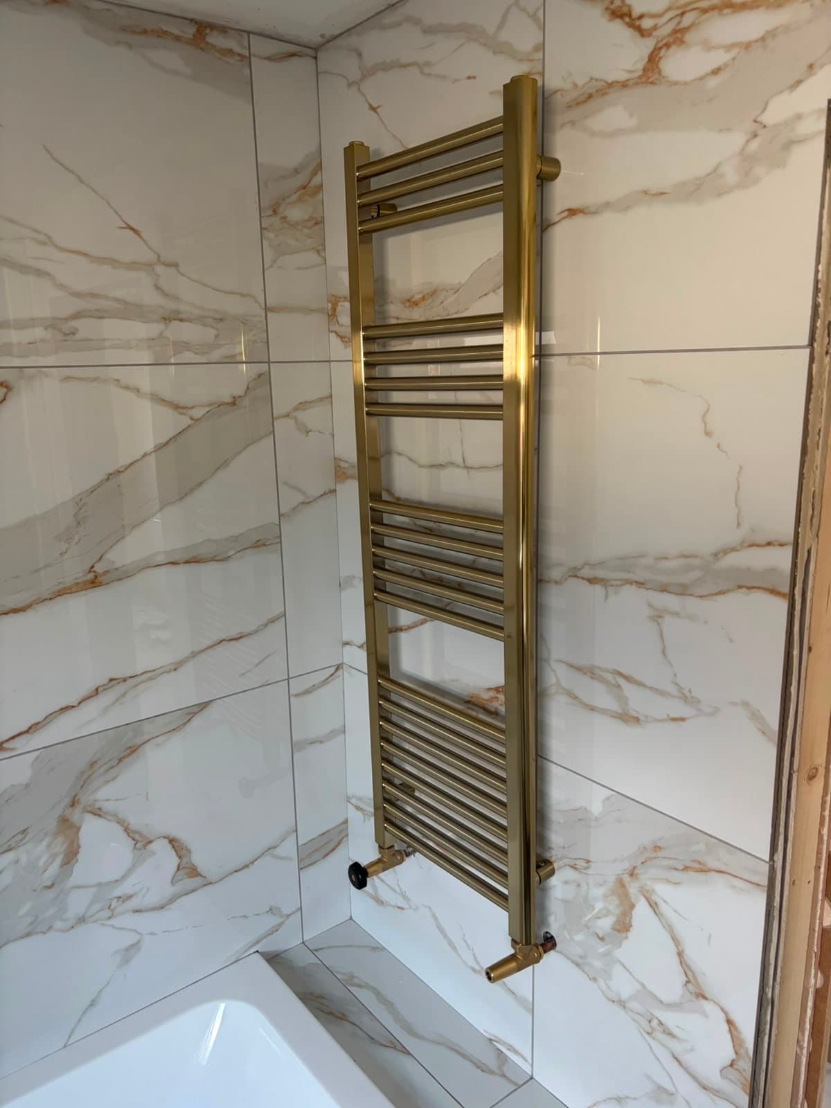 Brass heated towel rail beside the bath