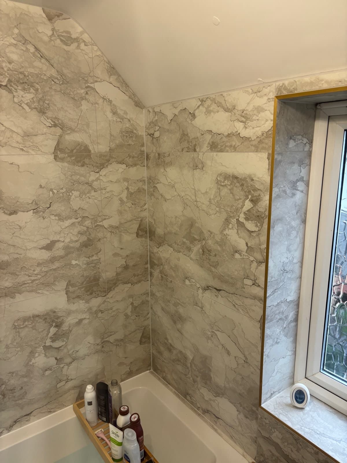 Marble-effect bathroom with a bath under the window