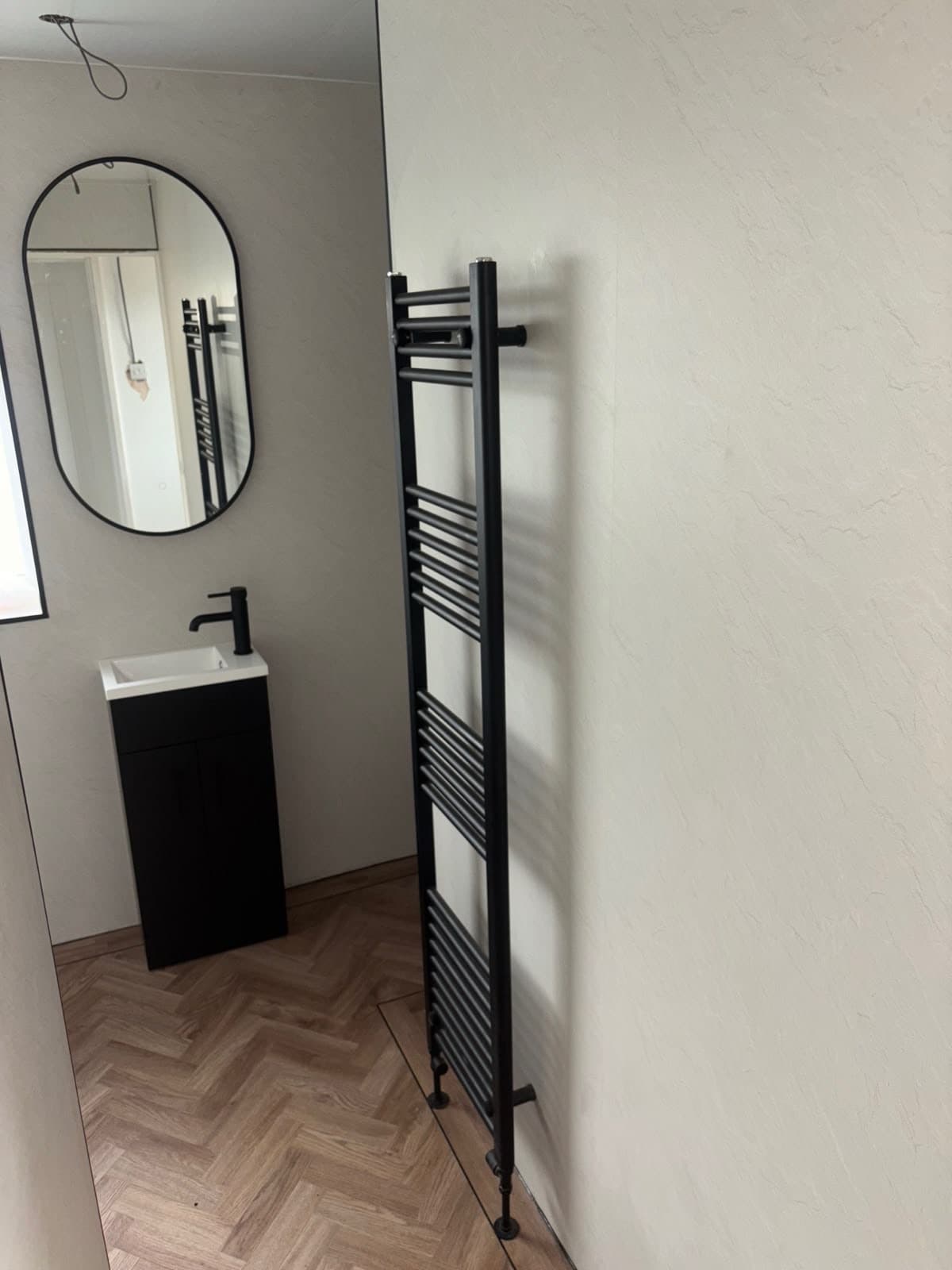 Cloakroom with a black towel rail and round mirror