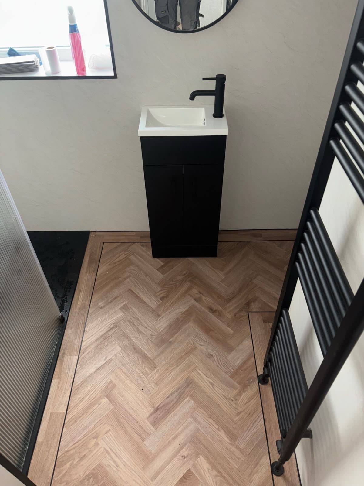Cloakroom with herringbone flooring and a black towel rail