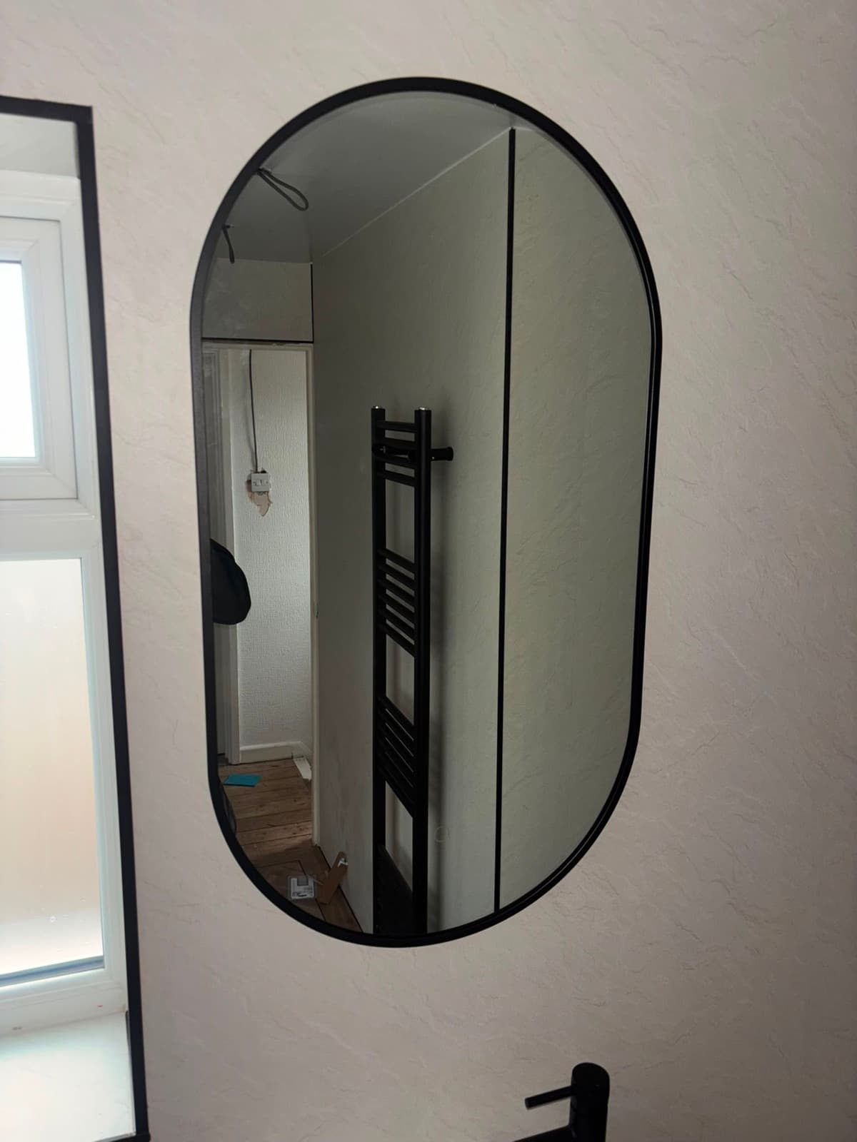 Oval black-framed bathroom mirror