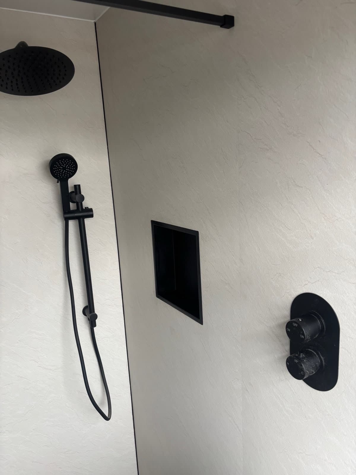Black shower fittings on a panelled wall