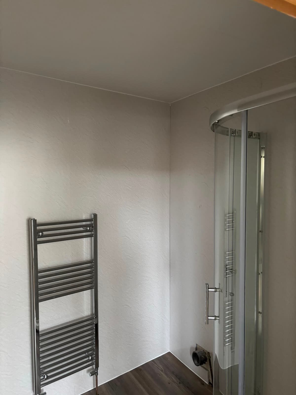 Shower enclosure beside a white towel rail
