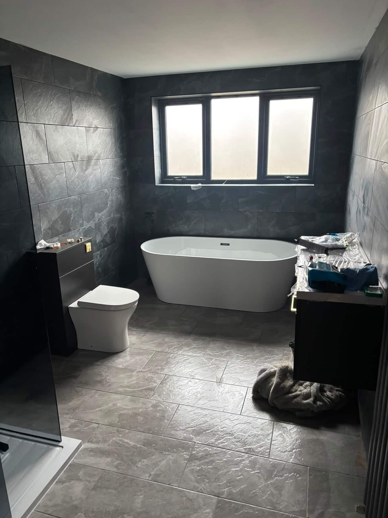 Dark-tiled bathroom with freestanding bath